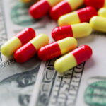 Red and yellow capsules on top of U.S. currency