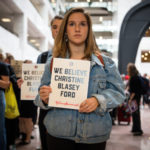Protestor in Senate office building holding sign "We believe Christine Blasey Ford"