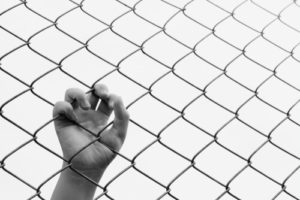 Hand gripping chain-link fence