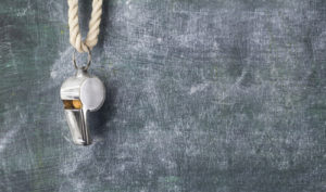 Silver whistle hanging on cord in front of chalkboard