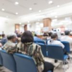 Rows of chairs with people waiting in hospital billing office