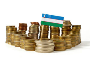Pile of coins with miniature flag of Uzbekistan