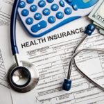 Health insurance forms, stethoscope, calculator and dollars