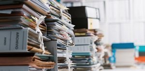 Disorganized paper records stacked on table