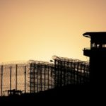 Prison tower and fence silhouetted against sky