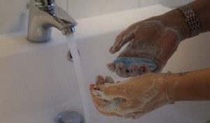 Soapy hands under running water faucet