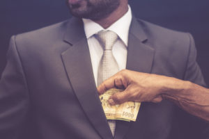 person pocketing money in a business suit