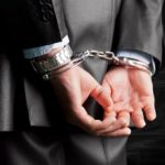 Hands in handcuffs behind back of white man in business suit
