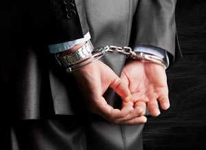 Hands in handcuffs behind back of white man in business suit