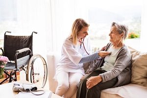 visiting nurse with elder woman sitting on a couch