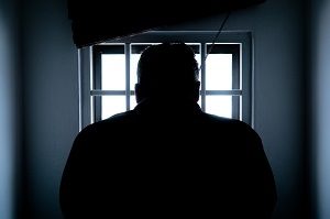 silhouette of man behind prison bars