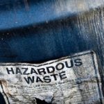 a waste barrel zoomed-in of a sticker saying "HAZARDOUS WASTE"
