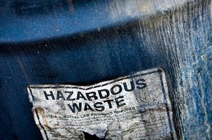 a waste barrel zoomed-in of a sticker saying "HAZARDOUS WASTE"