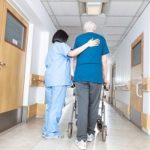 Nurse helping elder man walking in rehab facility