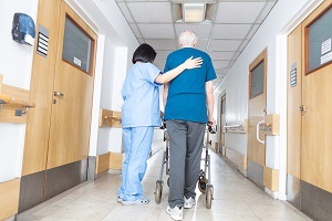 Nurse helping elder man walking in rehab facility