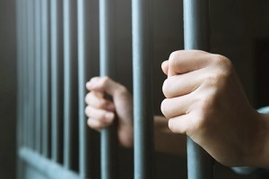 Hands grasping around prison bars