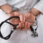 Doctor in handcuffs holding a stethoscope