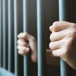 person holding onto prison bars