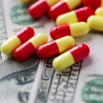 Red and yellow pills scattered on hundred dollar bills