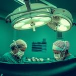 surgeons operating on patient under bright lights