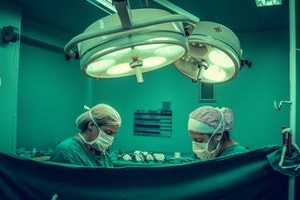 surgeons operating on patient under bright lights