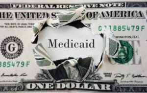 dollar bill with Medicaid text ripped through