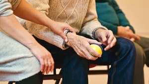 Woman holding elderly person's wrist