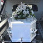 Whist Coffin in Hearse with White Flowers