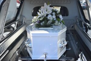 Whist Coffin in Hearse with White Flowers