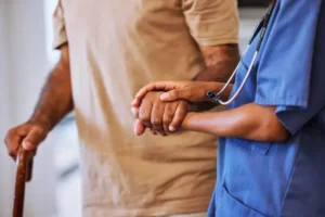 nurse helping walk older man with cane